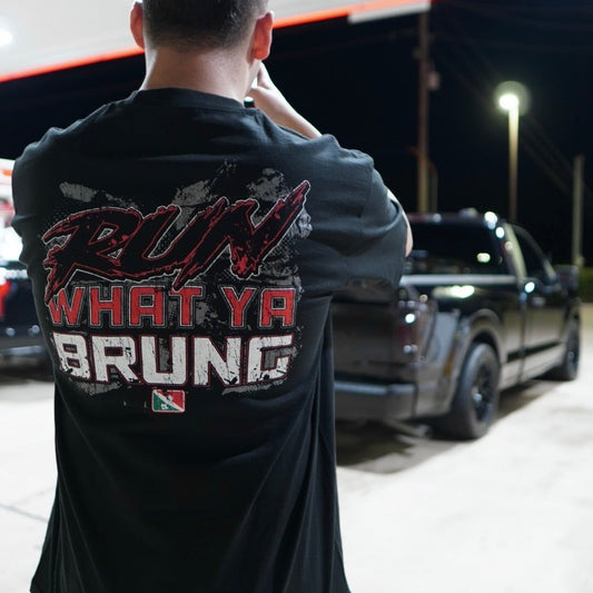 Person wearing a black t-shirt with text, standing in front of a truck at night.